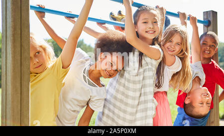 Les enfants multiculturels comme des amis tout en faisant de la gymnastique sur une jungle gym Banque D'Images