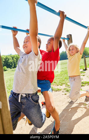 Trois garçons sont multiculturelles et shimmying doing gymnastics sur une jungle gym Banque D'Images