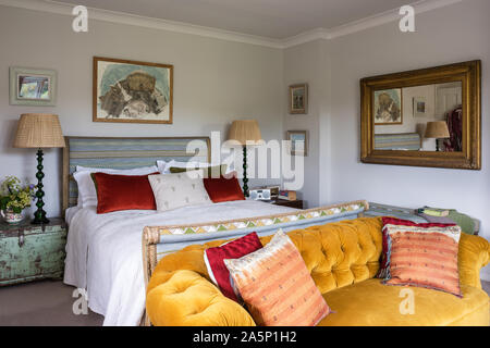 Coussins sur Chesterfield en velours avec un lit double et d''un miroir. Les murs de Farrow & Balls' Ammonite. Banque D'Images