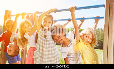 Groupe d'enfants joue ensemble en escalade sur une aire de jeux dans l'été Banque D'Images