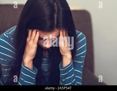 Femme malheureuse avec maux de tête assis et ne veut pas entendre quoi que ce soit à fermé les oreilles les doigts. Closeup portrait de personne d'affaires. Dure journée. T Banque D'Images