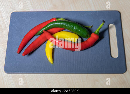 Chili Peppers. Hot Chili Peppers multicolores sur une planche à découper . Le point de droit. Banque D'Images