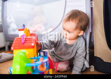 Mignon petit bébé jouant avec des jouets dans la salle de séjour sur une moquette.