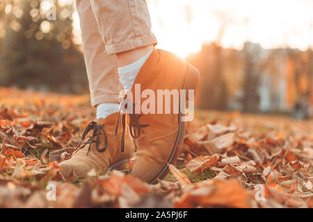 Les jambes des femmes dans d'élégantes Bottes nubuck d'automne. Au coucher du soleil dans la ville. Banque D'Images