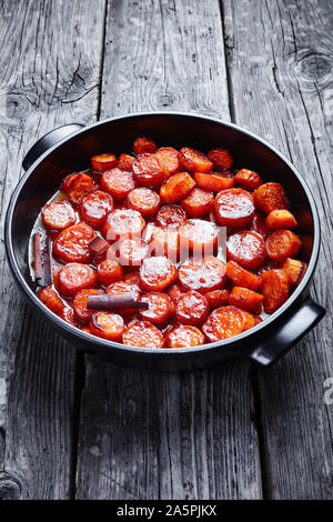 Confit d'ignames, patates douces cuites avec de l'action de la cannelle, le sucre brun et le beurre dans un plat de céramique noire, vue verticale Banque D'Images