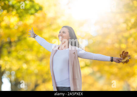 Bonheur femme in autumn park holding bouquet avec des feuilles d'automne. Banque D'Images