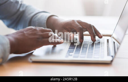 Méconnaissable african american man typing on laptop keyboard in office Banque D'Images