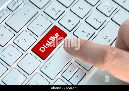 N'aiment pas le bouton du clavier. Un doigt appuie sur un bouton de couleur gris argent sur un clavier d'un ordinateur portable moderne. Bouton avec inscription close up.s. Banque D'Images