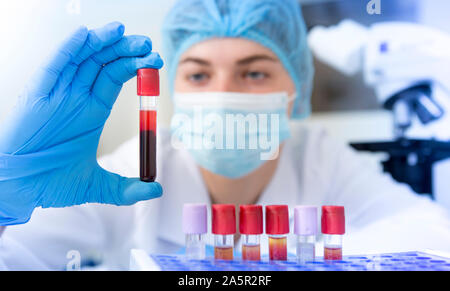 Woman scientist holding tube échantillon de sang à partir d'un rack Banque D'Images
