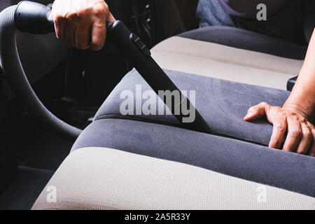 L'homme travailleur nettoyer la poussière à l'intérieur vide de l'intérieur après lavage de voiture Banque D'Images