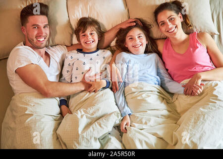 Famille heureuse avec deux enfants ensemble dans la matinée dans le lit dans la chambre à coucher Banque D'Images