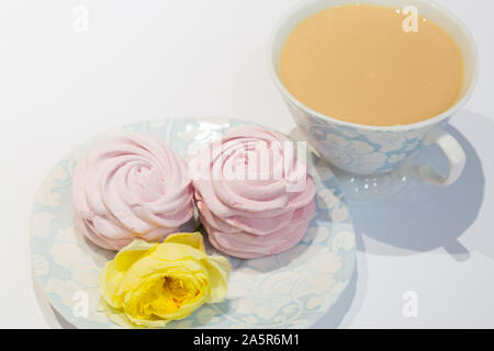 L'heure du thé avec des marshmallow rose. Thé noir avec du lait, doux souffle et rose jaune. Banque D'Images