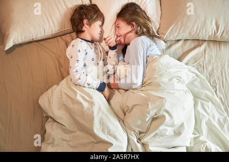 Frère et soeur sont au lit dans la chambre à coucher et bête heureusement autour Banque D'Images