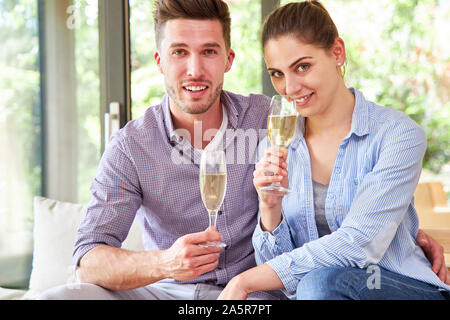 Jeune couple sympathique est de boire un verre de vin pétillant ensemble dans la salle de séjour Banque D'Images