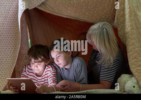 Petit-fils de mamie et les enfants avec e-book, tablette ou ordinateur dans la tente confortable Banque D'Images