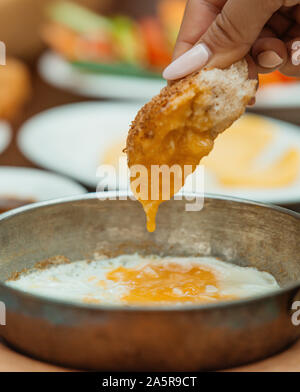 Femme trempant dans pain d'oeufs au plat sur le cuivre pan Banque D'Images