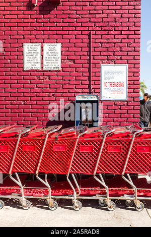 Une rangée de caddies rouge se cacher d'un publiphone monté sur le mur extérieur d'un super marché dans la petite havane, Miami, Floride Banque D'Images