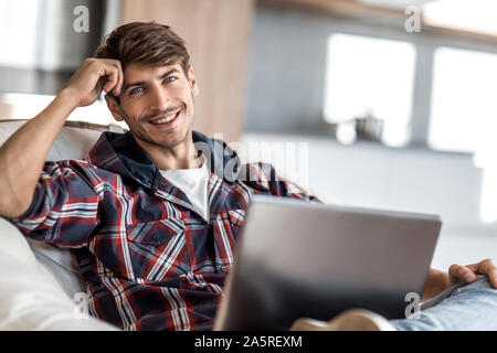 Close up. rêver jeune homme assis en face d'un ordinateur portable ouvert Banque D'Images