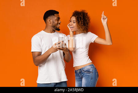 Jeune black couple enjoying musique favorite on cellphone Banque D'Images