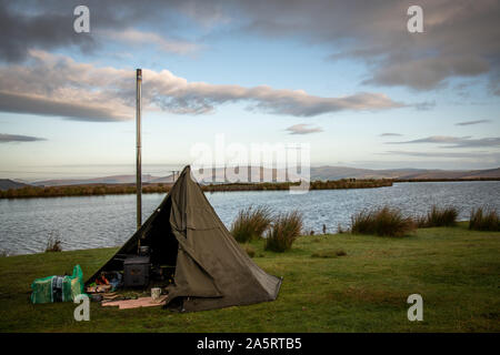 Wilding camping, tente avec poêle à bois à côté d'un lac de Brecon Beacons, Wales UK Banque D'Images