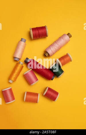 Couleur multi-thread spools ou accessoires de couture sur un fond jaune. Position verticale Banque D'Images