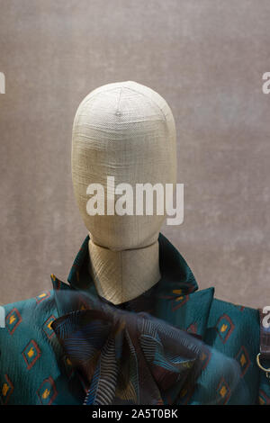 Mannequin en tissu, tête chauve , avec un grand arc sombre. Mannequin de chiffon dans une vitrine d'un magasin à la mode Banque D'Images