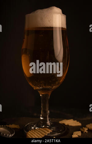 Plein verre de bière dans un cadre sombre. Banque D'Images