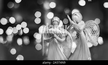 Deux anges priant de paille sur un fond de Noël floue. Beau bokeh créé par des lumières de Noël. Fait à la main traditionnelle poupée comme un tre de Noël Banque D'Images