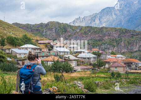 Avis de femme par derrière avec sac à dos, prendre une photo avec téléphone portable de village de kazbegi stepantsminda sur la façon de suivre à l'église Trinity Banque D'Images