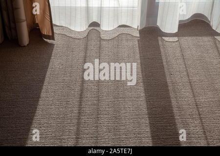 L'ombre sur la moquette de la chambre. Le soleil brille à travers les rideaux dans la salle de séjour Banque D'Images