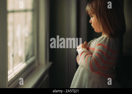 Girl looking out window boutonnant sweater Banque D'Images