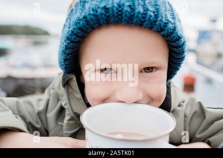 Portrait d'un jeune garçon de boire du chocolat chaud à l'extérieur Banque D'Images