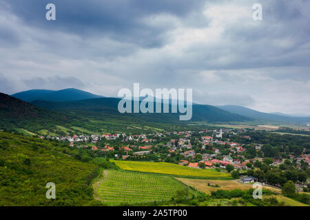 Petit village dans une vallée. Collines, montagnes et champs autour. Jour d'été. Photo prise du flanc de la colline. Banque D'Images