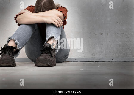 Jeune femme pleure et s'assis près d'un mur vide, triste et déprimé lonely girl holding sa tête vers le bas Banque D'Images