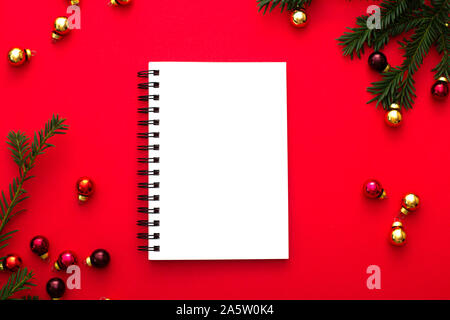 Maquette blanche portable sur fond rouge avec des décorations de Noël d'or et vert sapin brunch. Flatlay style. Banque D'Images