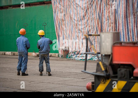 Deux male construction workers standing dans une cour d'expédition. Banque D'Images
