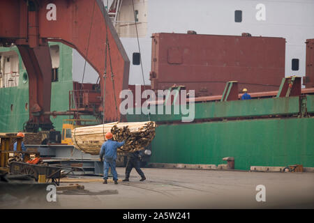 Deux male construction workers raccordement de câbles à une grue dans un chantier maritime. Banque D'Images