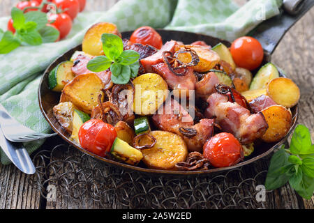 Un repas de remplissage : Poêlée de pommes de terre non pelées bébé avec des légumes et du cou de porc, servi dans une poêle de fer Banque D'Images