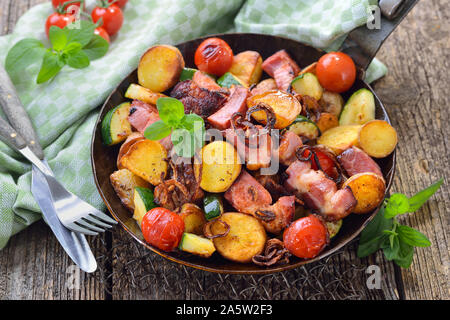 Un repas de remplissage : Poêlée de pommes de terre non pelées bébé avec des légumes et du cou de porc, servi dans une poêle de fer Banque D'Images