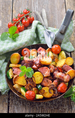 Un repas de remplissage : Poêlée de pommes de terre non pelées bébé avec des légumes et du cou de porc, servi dans une poêle de fer Banque D'Images