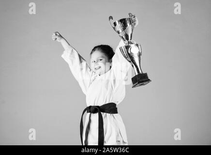 Le succès du sport. La formation pour être le meilleur. Petite fille avec champion cup. arts martiaux Kung Fu pratique. enfance heureuse. winner petite fille dans gi sportswear. Masquage. l'énergie et de l'activité pour les enfants. Banque D'Images