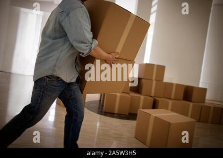 Young adult man carrying boxes dans un bâtiment. Banque D'Images