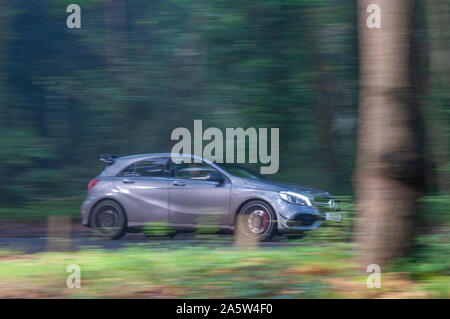 Mercedes Benz GRIS A45 AMG voiture conduit à travers les arbres d'automne sur un chemin de campagne avec un arrière-plan flou Banque D'Images