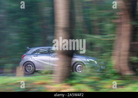 Mercedes Benz GRIS A45 AMG voiture conduit à travers les arbres d'automne sur un chemin de campagne avec un arrière-plan flou Banque D'Images