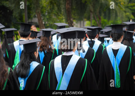 Vue arrière du groupe de diplômés universitaires en robes noires s'aligne pour le diplôme à l'université cérémonie de remise de diplômes. L'éducation Concept félicitations, stu Banque D'Images