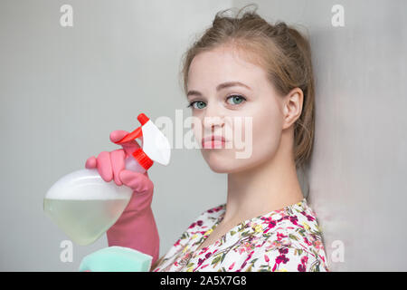 Jeune fille femme de race blanche avec des gants en caoutchouc et le pulvérisateur, le nettoyage de la maison Banque D'Images
