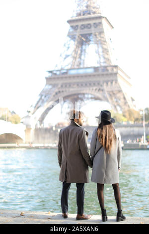 Vue arrière de l'afro-américain et de l'homme fille debout près de la Tour Eiffel à Paris. Banque D'Images