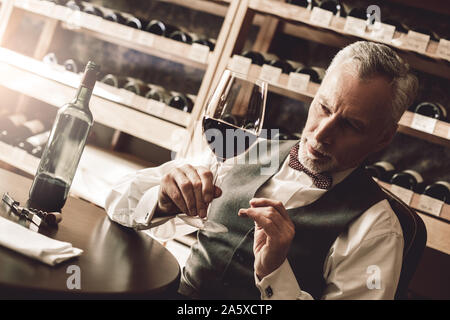 Sommelier Concept. Senior contrôle qualité de vin rouge pensive Banque D'Images