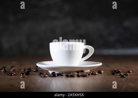 Impression photo d'un verre de café blanc entouré de graines de café sur une table en bois - Close-up Banque D'Images