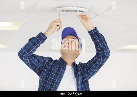 Homme mûr de l'installation au plafond ventilation grill Banque D'Images